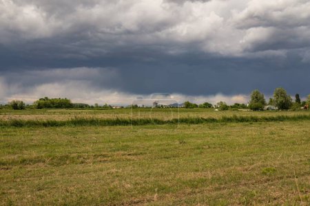Dunkle Gewitterwolken ziehen über heiterem Ackerland auf und schaffen eine dramatische ländliche Szenerie.