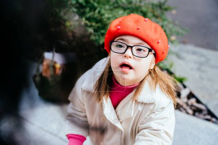 Photo for Cute inquisitive little girl in eyeglasses with special needs looking at mother. Portrait of beautiful little girl in red beret - Royalty Free Image
