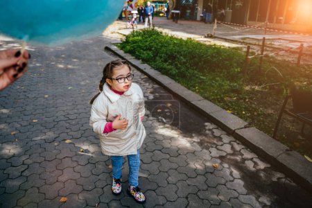 Téléchargez les photos : Portrait pleine longueur de belle jeune fille avec deux tresses à lunettes, manteau blanc souriant profitant du beau temps ensoleillé dans le parc d'automne en plein air. - en image libre de droit