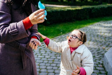 Téléchargez les photos : Triste petite fille pleurant avec deux tresses dans des lunettes de vue regardant mère méconnaissable au parc d'automne en plein air. - en image libre de droit