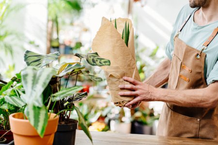 Foto de Vendedor irreconocible, empleado vendiendo plantas en macetas en una tienda de flores. Pequeños empresarios. - Imagen libre de derechos