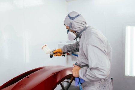 Un disparo auténtico. Pintor de coches reparador pintor en cámara pintura automóvil coche parachoques en servicio de coche.