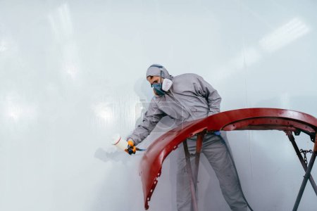 Un disparo auténtico. Pintor de coches reparador pintor en cámara pintura automóvil coche parachoques en servicio de coche.