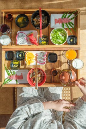 Foto de Mujer manos verter té en taza de cerámica antes de comer comida de Japón - Imagen libre de derechos