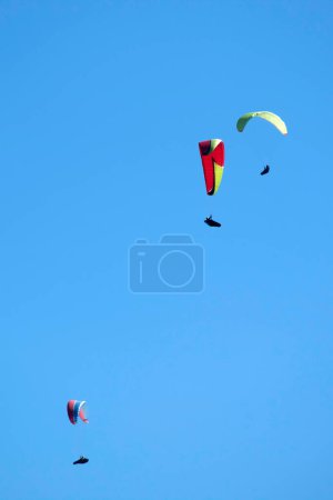 Foto de Documentación fotográfica del momento de vuelo de un grupo de parapentes lanzados al cielo azul - Imagen libre de derechos