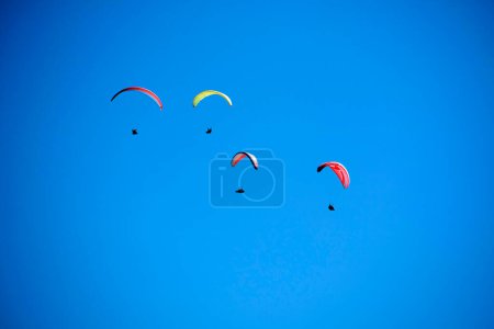 Foto de Documentación fotográfica del momento de vuelo de un grupo de parapentes lanzados al cielo azul - Imagen libre de derechos