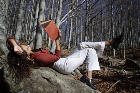 Foto de Documentación fotográfica de una hermosa niña que intenta leer en un bosque en la temporada de otoño - Imagen libre de derechos