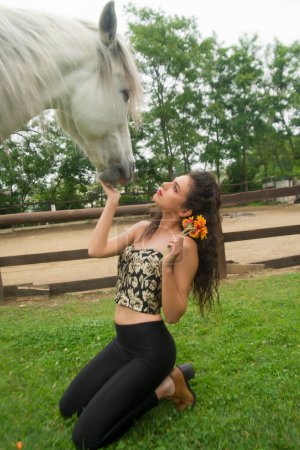 Foto de Documentación fotográfica que retrata a una hermosa chica mientras acaricia un caballo blanco - Imagen libre de derechos