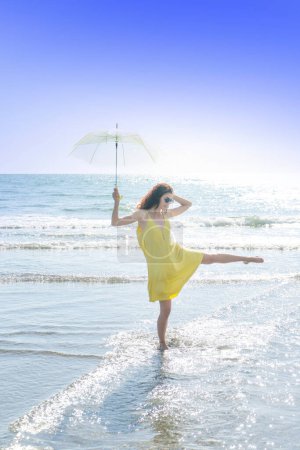 Foto de Hermosa chica morena bailando junto al mar con un paraguas abierto - Imagen libre de derechos