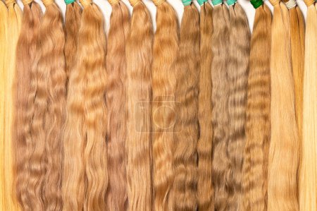 Foto de Natural tonos claros ondulados cabello humano en paquetes con varios tonos se utiliza en la industria de la belleza para las extensiones y la fabricación de pelucas. - Imagen libre de derechos