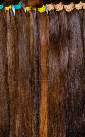 Téléchargez les photos : Bundles de cheveux sains naturels de couleur chocolat de divers naturels pour l'extension. Image verticale. Gros plan. - en image libre de droit