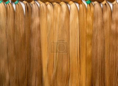 Téléchargez les photos : Cheveux humains droits naturels dans des tons clairs en faisceaux avec différentes nuances de couleur de paille est utilisé dans l'industrie de la beauté pour les extensions. - en image libre de droit