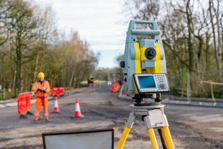 Photo for Site engineer operating his instrument during roadworks. Builder using total positioning station tachymeter on construction site for new road setting out - Royalty Free Image