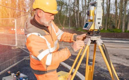 Photo for Site engineer setting his instrument during roadworks. Builder installing total positioning station tachymeter on construction site for new road setting out - Royalty Free Image