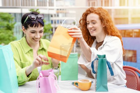 Téléchargez les photos : Les femmes avec des sacs colorés s'amuser avec des achats dans la ville urbaine. Consommation, vente, achats, achats, mode de vie concept. - en image libre de droit