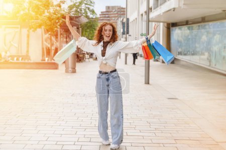 Téléchargez les photos : Femme heureuse avec des sacs colorés s'amuser avec des achats dans la ville urbaine. Consommation, vente, achats, achats, mode de vie concept. - en image libre de droit