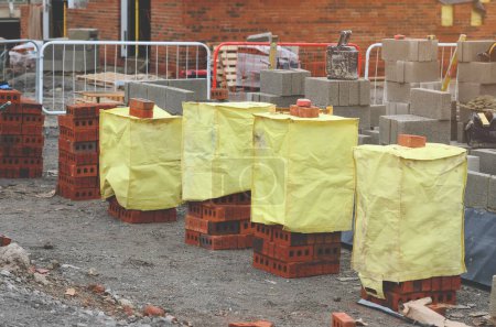 Rote Ziegel und Betonblöcke auf der Baustelle angeliefert und neben der Arbeitsstelle bereit für Maurer platziert
