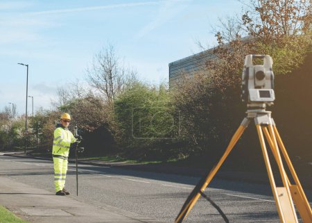 Surveyor doing road survey using modern robotic total station EDM before beginning of construction works and setting construction site