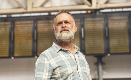 frustrado hombre sosteniendo un teléfono inteligente mientras que en la estación de tren y el tren está llegando, concepto de viaje