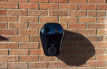Private electric vehicle charging station fitted to the face of a red brick wall