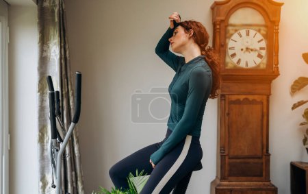 Mujer joven entrenando en casa usando elíptica cross trainer
