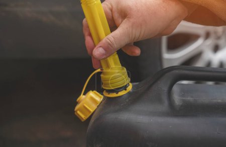 Photo for A man filling fuel tank of his car with diesel fuel from the jerry can as there is no fuel at the petrol station, close up - Royalty Free Image