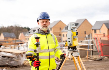 Photo for Surveyor builder site engineer with theodolite total station at construction site outdoors during surveying work - Royalty Free Image