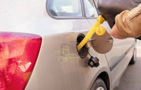 Photo for A man filling the fuel tank of his car with diesel fuel from the jerry can as there is no fuel at the petrol station, close up. The fuel crisis is continue - Royalty Free Image