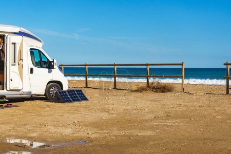Foto de Caravan rv camping on beach, portable solar photovoltaic panel, charging battery at camper car rv - Imagen libre de derechos