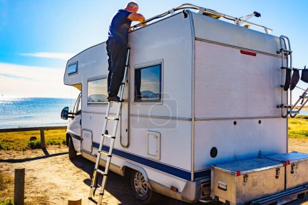 Téléchargez les photos : Homme à l'échelle à la caravane. Réparation caravane camping-car toit. - en image libre de droit