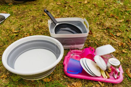 Many clean dishes drying outdoor. Washing up on fresh air. Camping on nature, dishwashing outside.