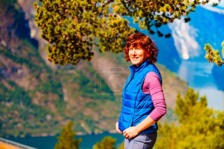 Photo for Tourist woman on the mountain top looking at view of fjord mountains, Norway. National tourist scenic route Aurlandsfjellet. Holidays relaxation on trip. - Royalty Free Image