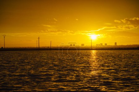 Sonnenuntergang über der Küste mit Stadtsilhouette. Küstenlandschaft in goldenen Stunden, San Pedro del Pinatar, Murcia Spanien.