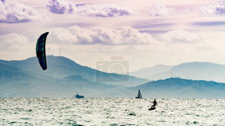 Photo for Kiteboarding. Kite surfer rides waves, Tarifa, Cadiz in Spain. Sports activity. Kitesurfing action. - Royalty Free Image