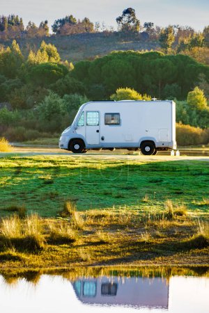 Camping on nature. Camper vehicle at lake shore reflecting in water. Povoa e Meadas Dam in Castelo de Vide, Alentejo Portugal. Travel in motor home.