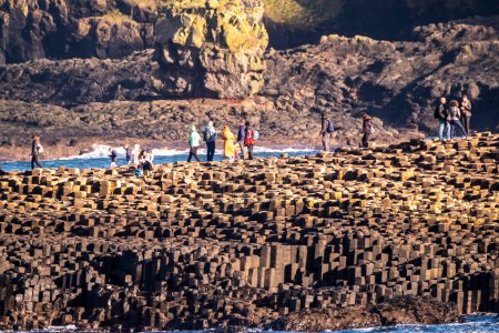 Foto de GIANTS CAUSEWAY, IRLANDA DEL NORTE, Reino Unido - 05 DE NOVIEMBRE DE 2022: Gente disfrutando de las 40000 columnas de basalto entrelazadas. - Imagen libre de derechos