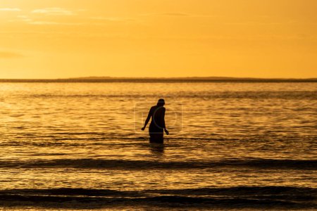 Photo for Silhouette of female swimmer going into the Atlantic ocean in Ireland. - Royalty Free Image