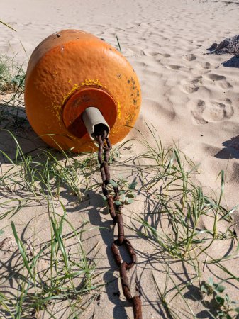 Téléchargez les photos : Bouée orange couchée sur la plage à marée basse. - en image libre de droit