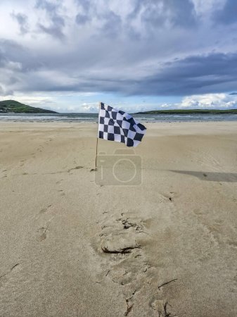 Foto de Revisada bandera blanca y bandera de carreras en Narin strand por Portnoo, Condado de Donegal, Irlanda. - Imagen libre de derechos