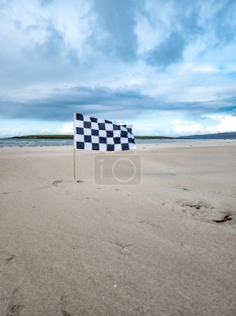 Foto de Bandera blanca y negra ondeando en la playa de arena. - Imagen libre de derechos