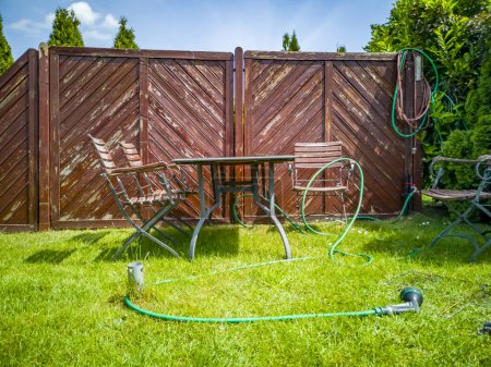 Photo for BBQ grillage rost and hose lying on the wet lawn. - Royalty Free Image