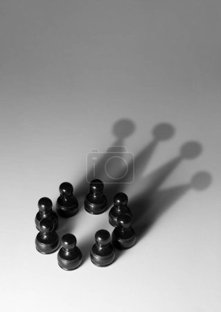 Photo for Group of black pawns with shadow shaped as a crown - Royalty Free Image