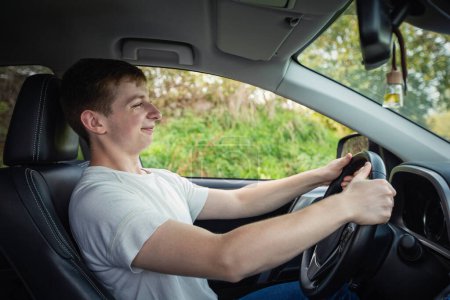 Orgulloso y alegre joven conductor en frente del volante de conducción de su nuevo coche con confianza