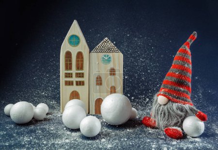 Téléchargez les photos : Elfe décorateur de Noël, nain tenant une boule de neige devant le bâtiment. concept de délices d'hiver, scène de fond de vacances - en image libre de droit