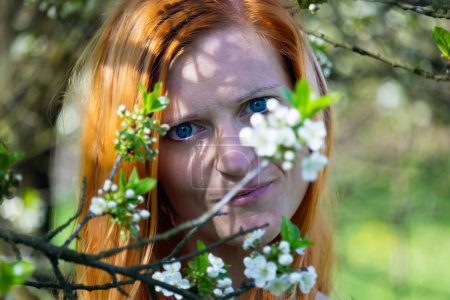 Photo for Portrait of beauty young redhead woman in cherry blossom orchard front view - Royalty Free Image