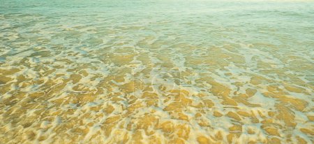 Ozeanhintergrund aus seichtem Meerwasser, das schäumt und Sand aufwirbelt