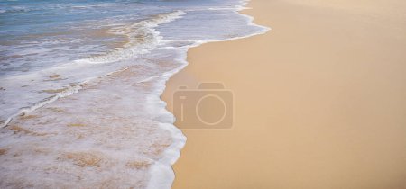 Eine Strandszene, die sich als Hintergrundteller für Bilder am Meer eignet, mit Wellen aus Sand, Brandung und weißem schäumendem Wasser auf nassem Sand