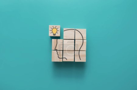 Foto de Esquema de cabeza humana en bloques de madera con bombilla de pieza faltante, resolución de problemas, creatividad, concepto de motivación - Imagen libre de derechos