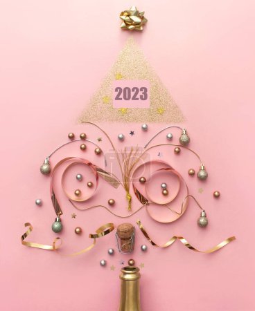 Foto de 2023 decoraciones de oro y bauble que sale de la botella de champán, la creación de una forma de árbol de Navidad, vacaciones concepto de celebración de año nuevo - Imagen libre de derechos