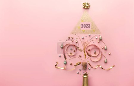 Foto de 2023 decoraciones de oro y bauble que sale de la botella de champán, la creación de una forma de árbol de Navidad, vacaciones concepto de celebración de año nuevo - Imagen libre de derechos